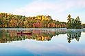 Senior man paddling a red wooden canoe on a beautiful northern Minnesota lake