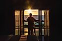 Woman open the door to see ocean sunrise view from bedroom balcony for travel concept.