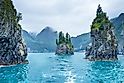 Blue waters and tree covered rocks jutting out of water on a cloudy morning at Porcupine bay at Kenai Fjords National Park, Alaska
