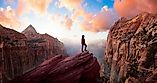 Woman at cliff's edge looking at a view of the Canyon at sunset. Taken in Zion National Park, Utah.