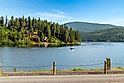 A motorboat with American flag on the lake with waterfront homes and docks behind at Lake Coeur d'Alene's Bennett Bay along the Centennial Trail