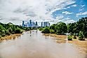High and fast water rising in Bayou River with downtown Houston in background