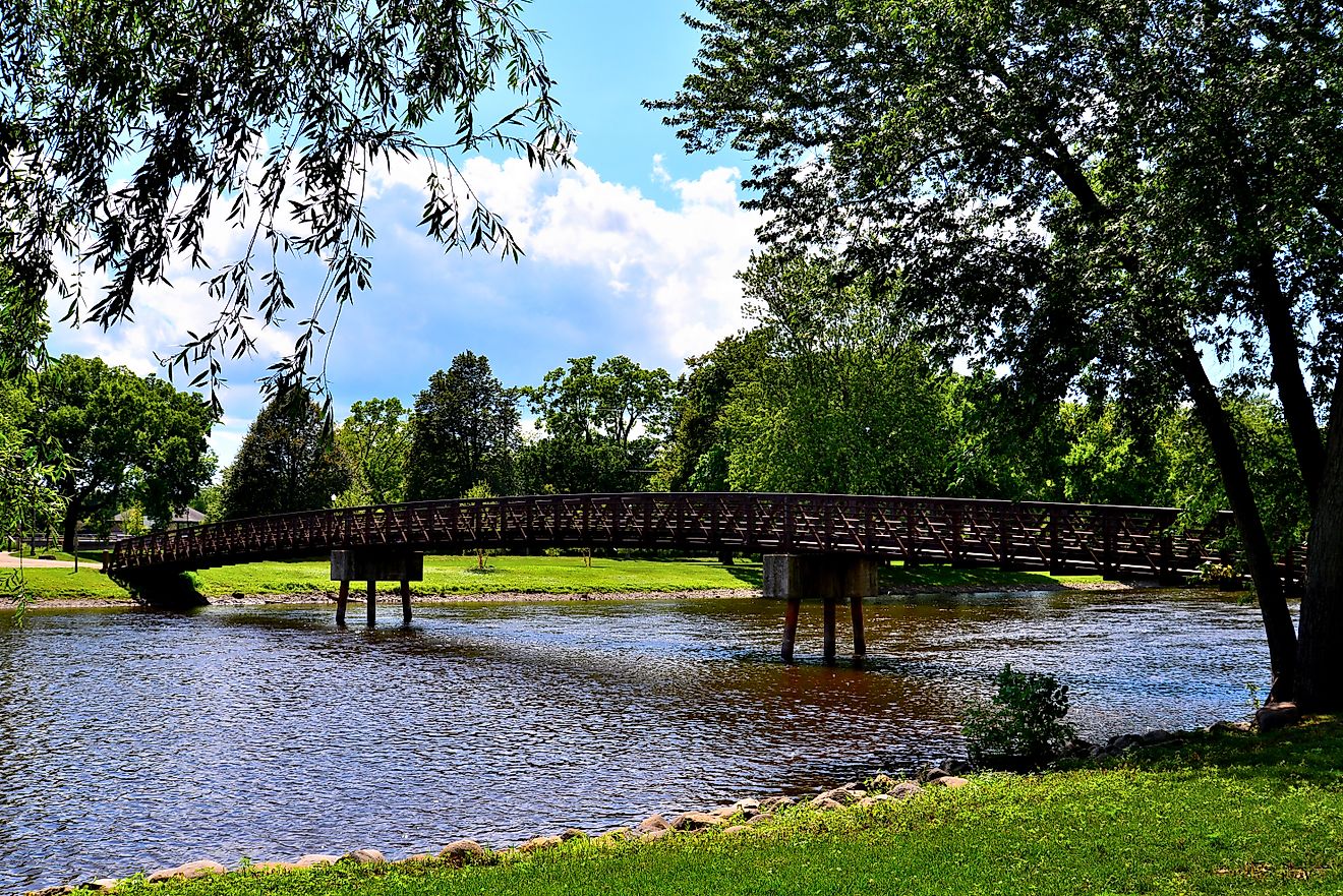 A long footbridge crossing the Fox River in Burlington Wisconsin Wehmhoff Jucker Park on a mid summer afternoon. 