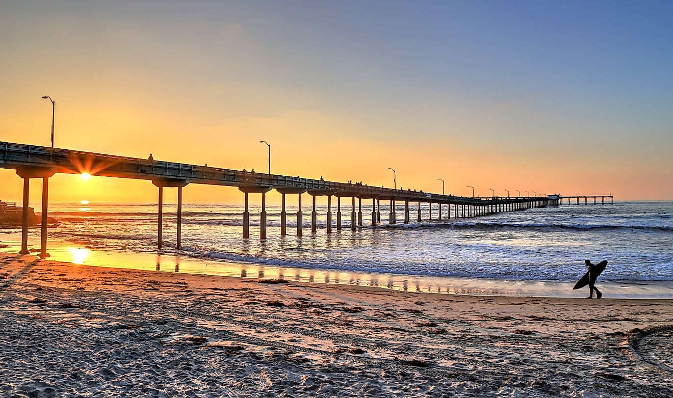 A surfer walks on Ocean Beach near the pier in San Diego, California.