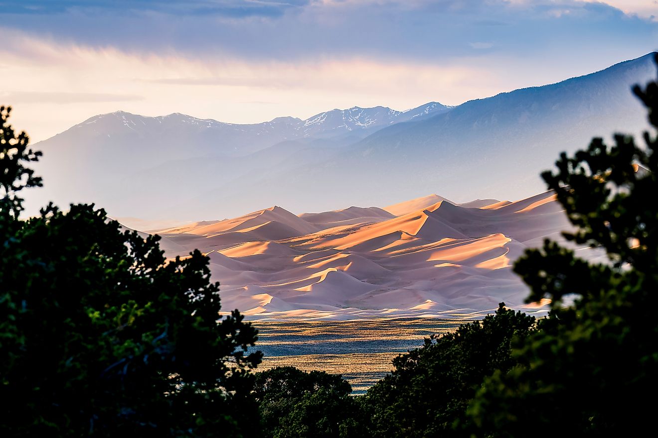 Scenic view of desert against cloudy sky at Great Sand Dunes National Park during sunset