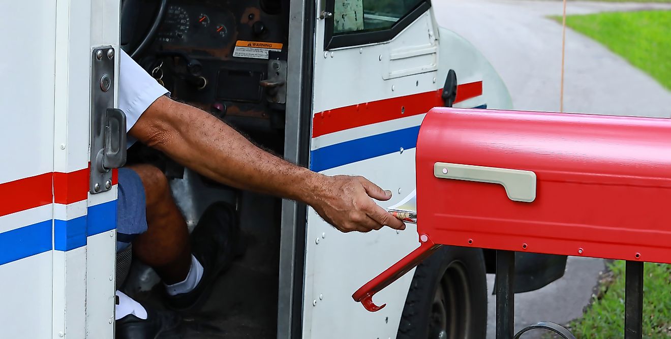 : Mail man reaches out of his truck to deliver mail. 