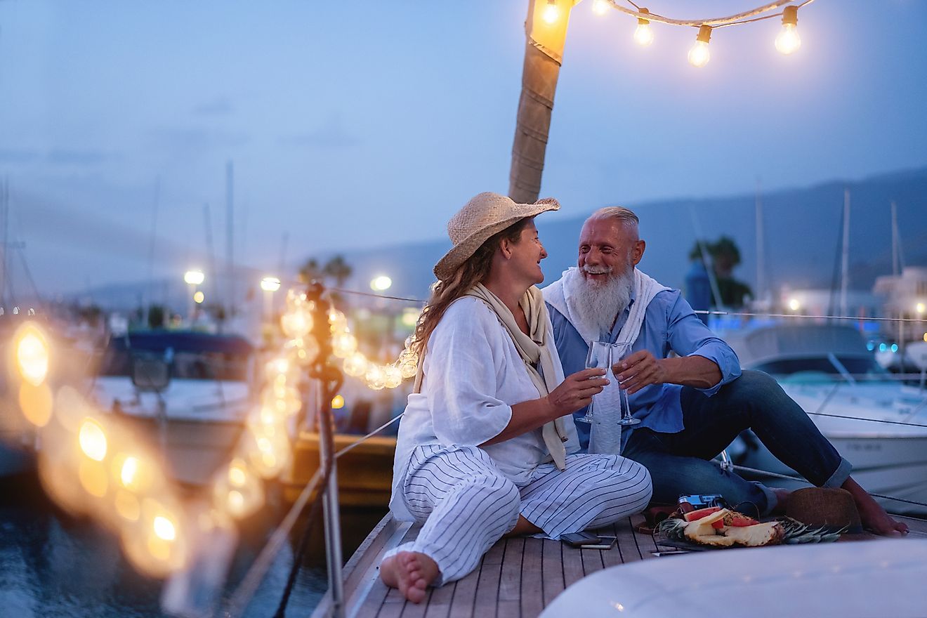 Senior couple cheering with champagne on a sailboat during wedding anniversary vacation