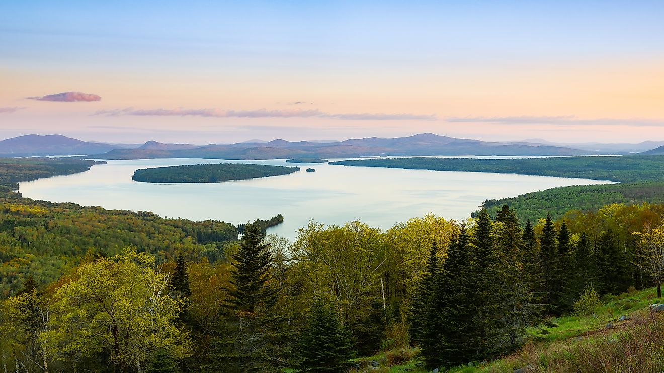 Height of Land Overlook at sunrise showing Mooselookmegunic Lake under clear sky with orange cast on the horizon during the summer.