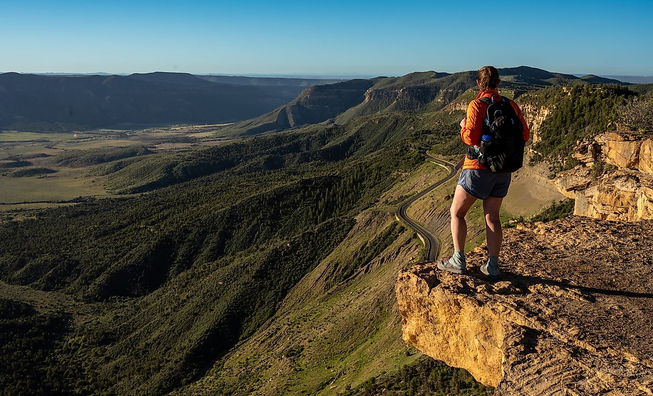 HIker Stands On Rock Shelf Looking Over Mesa Verde National Park