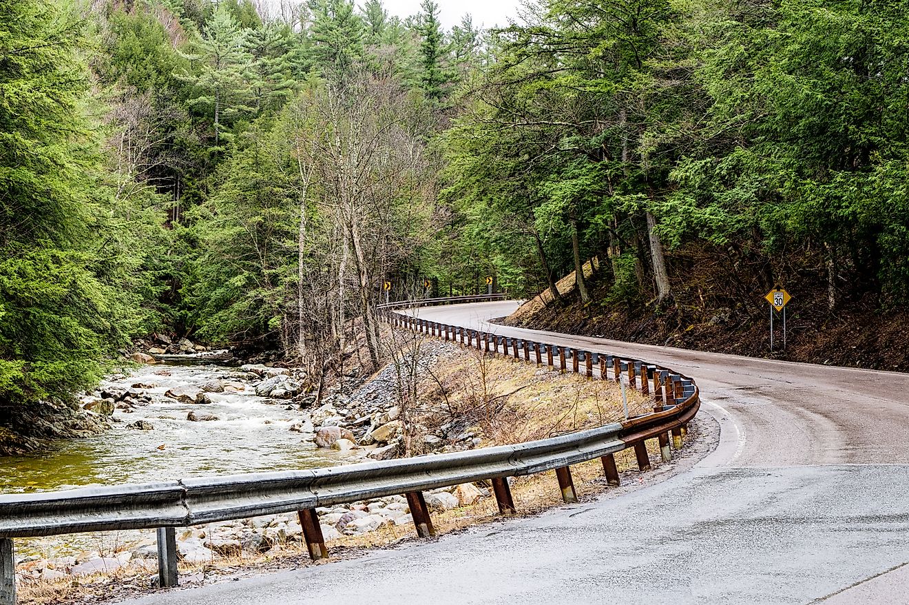 Mountain Road in Upstate New York: A narrow road curves beside a rushing stream at the eastern edge of the Adirondack Mountains in northeast New York.