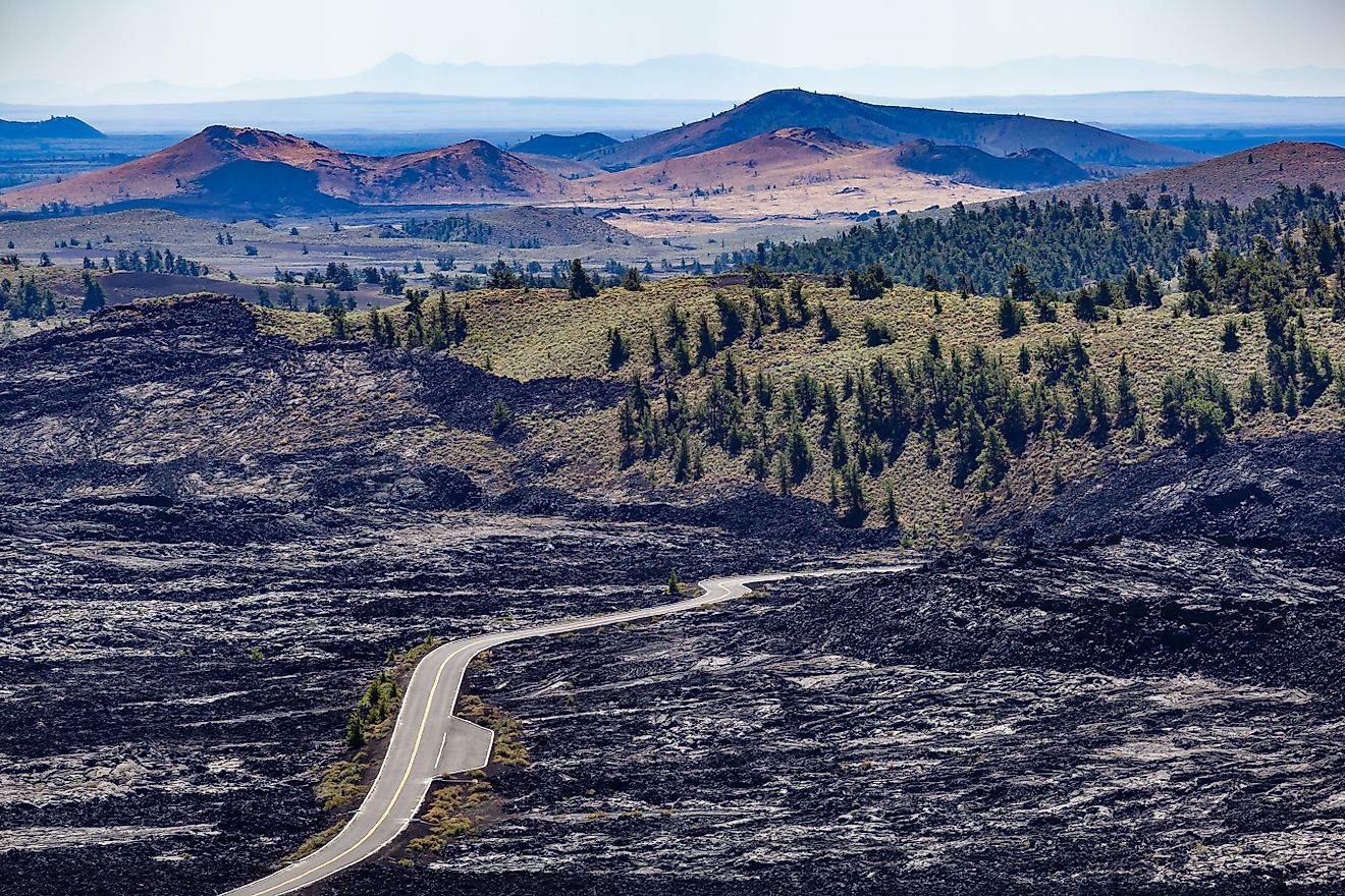 Road that runs between lava rocks and grasslands with pine trees. Craters of the Moon National Monument and Preserve is a United States National Monument and National Preserve on the Snake River Plain