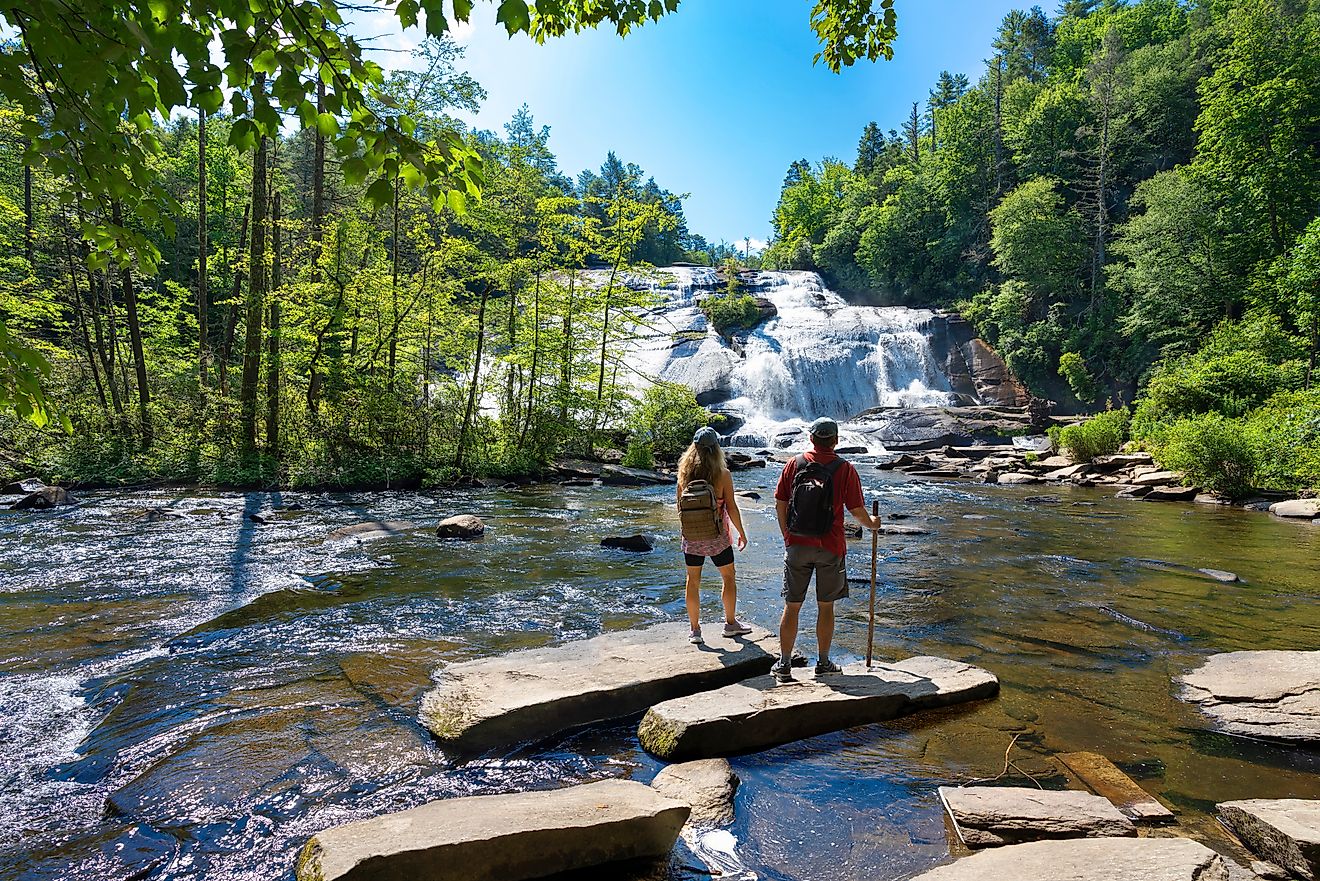 Couple enjoying beautiful waterfall view at Dupont State Forest, near Asheville, North Carolina.