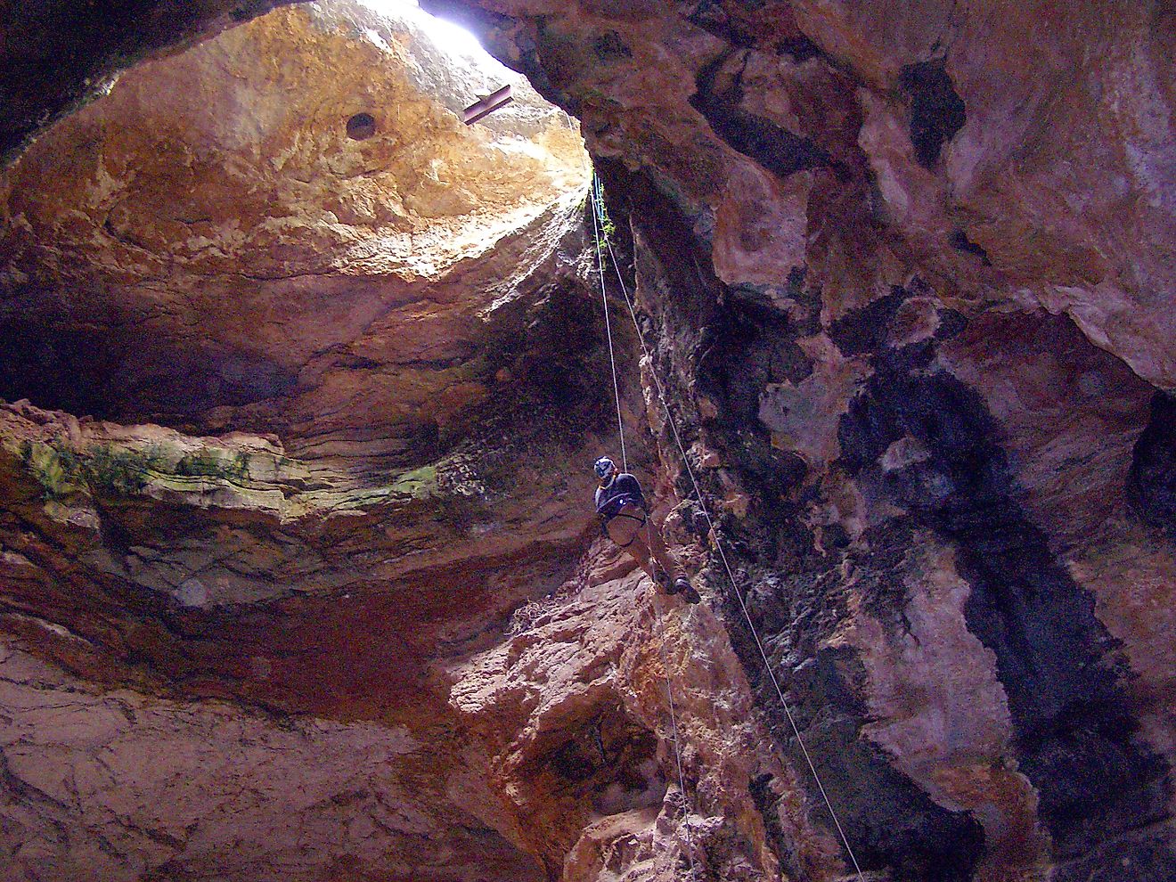 Entering the Natural Trap Cave — a large cave/hole that trapped falling prehistoric animals, located in the Bighorn Mountains foothills of Big Horn County, Wyoming. Editorial credit: Bureau  of Land Management, Public domain, via Wikimedia Commons