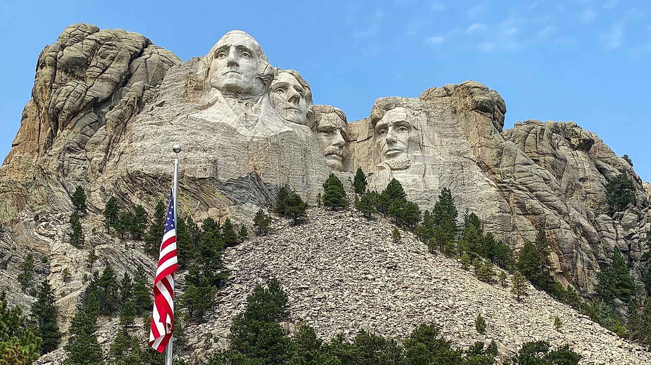mount rushmore and american flag against a blue sky