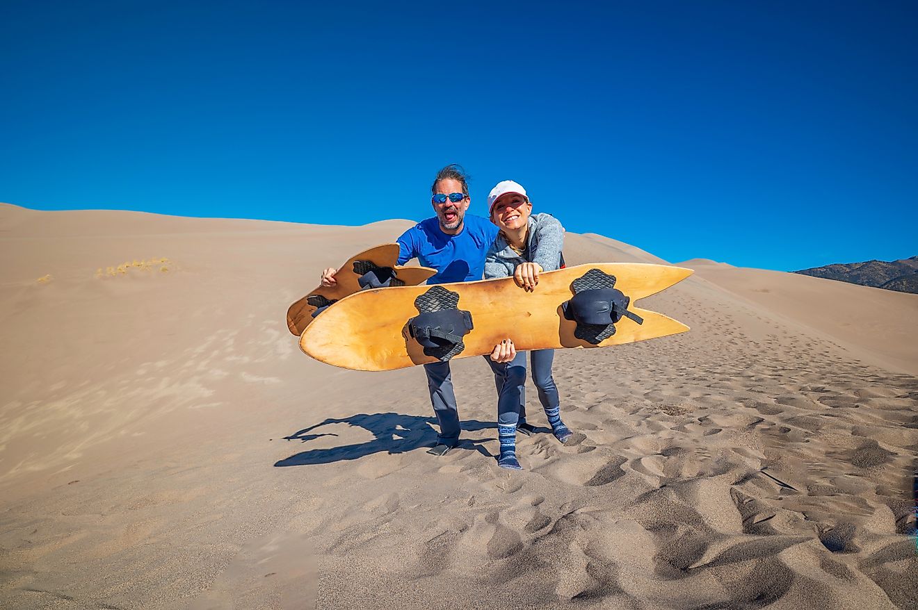 Happy couple holding sand boards at the Great Sand Dunes National Park