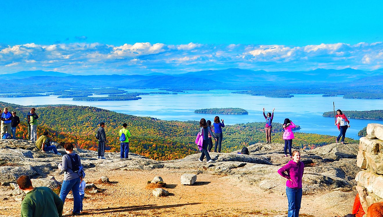Tourists posing for photos at the summit. Lake Winnipesaukee and the Belknap Mountains. Editorial credit: Helioscribe / Shutterstock.com