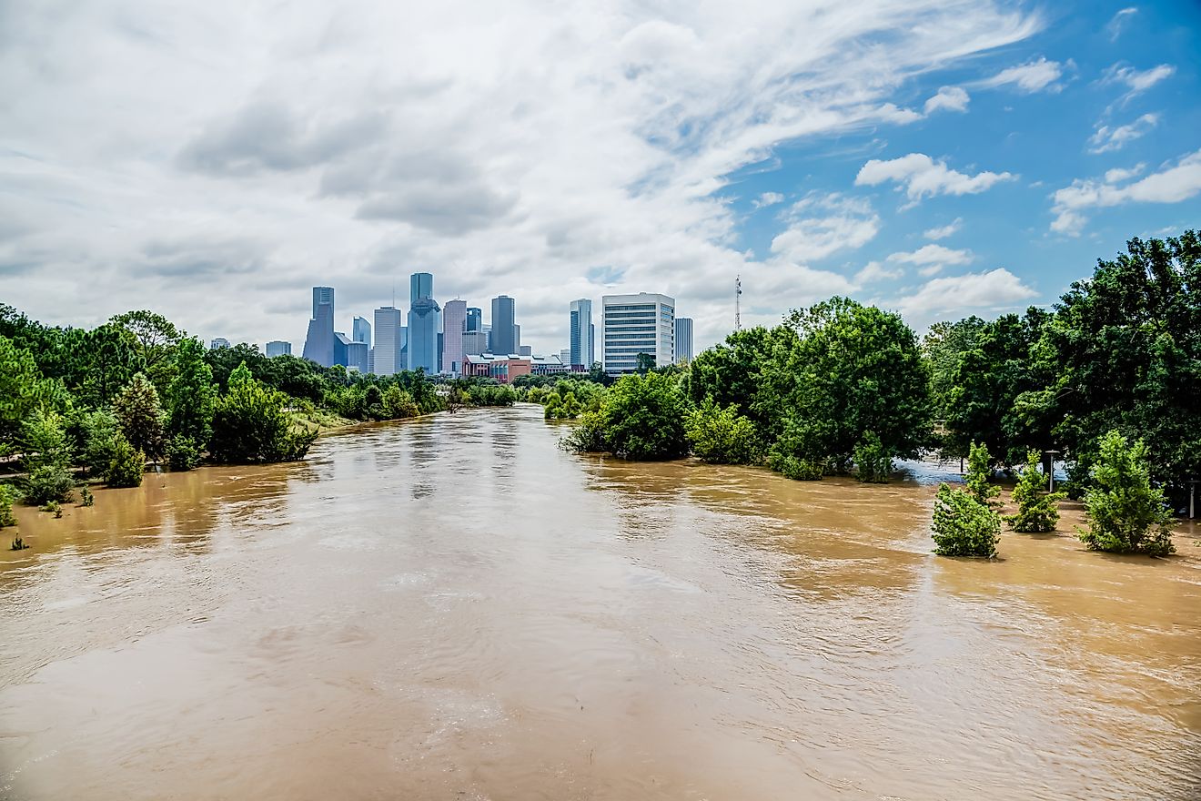 High and fast water rising in Bayou River with downtown Houston in background