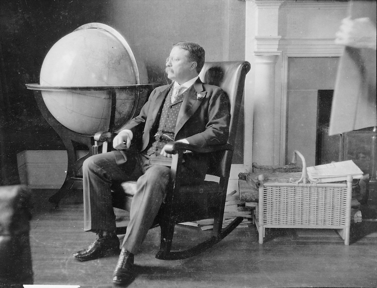 Theodore Roosevelt, at the end of his presidency, seated in rocking chair, by large globe.