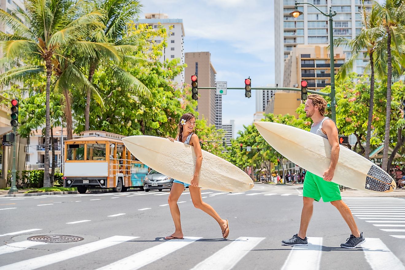 Honolulu Hawaii surfers couple tourists people walking crossing city street carrying surfboards going to the beach surfing