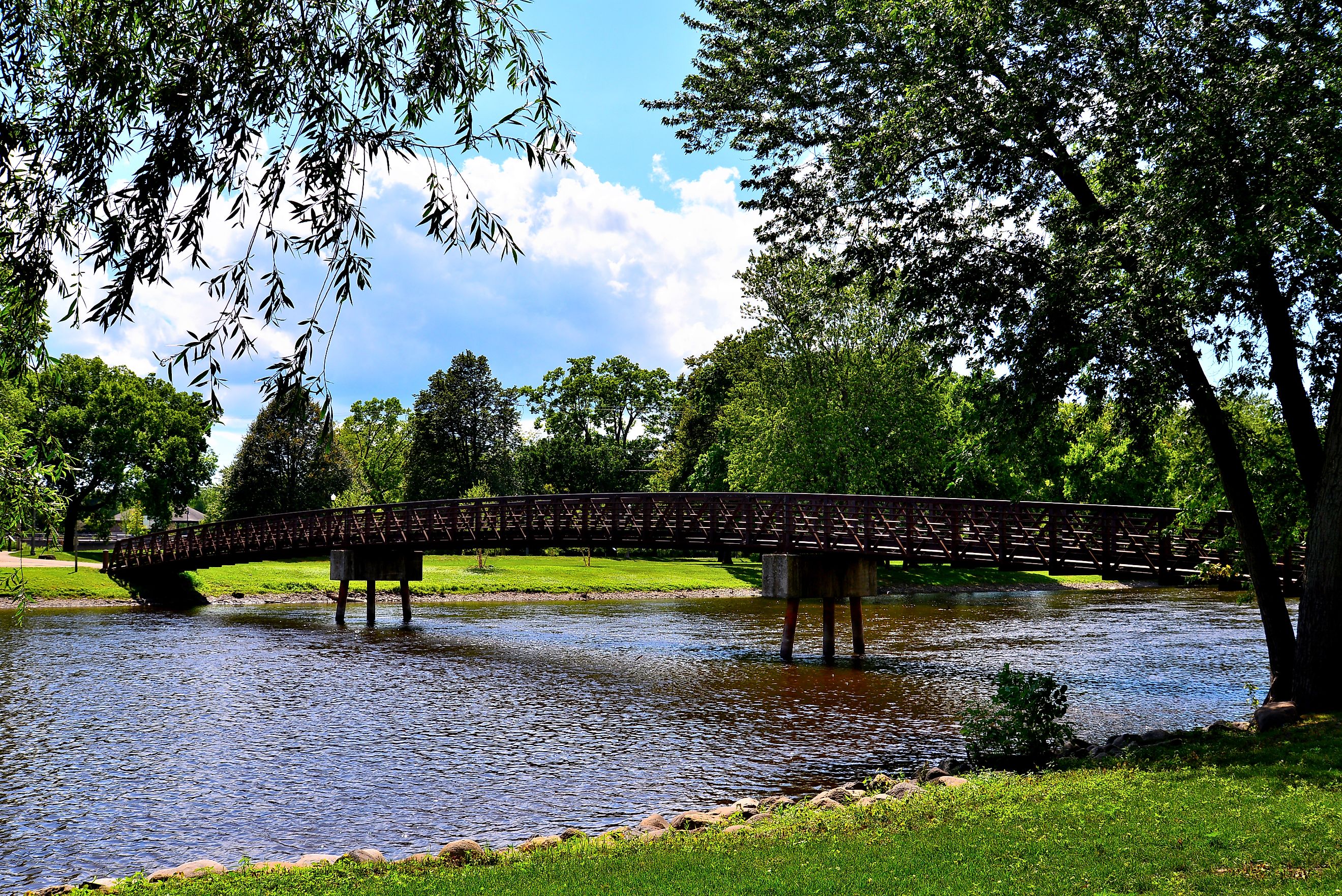 A long footbridge crossing the Fox River in Burlington Wisconsin Wehmhoff Jucker Park on a mid summer afternoon.