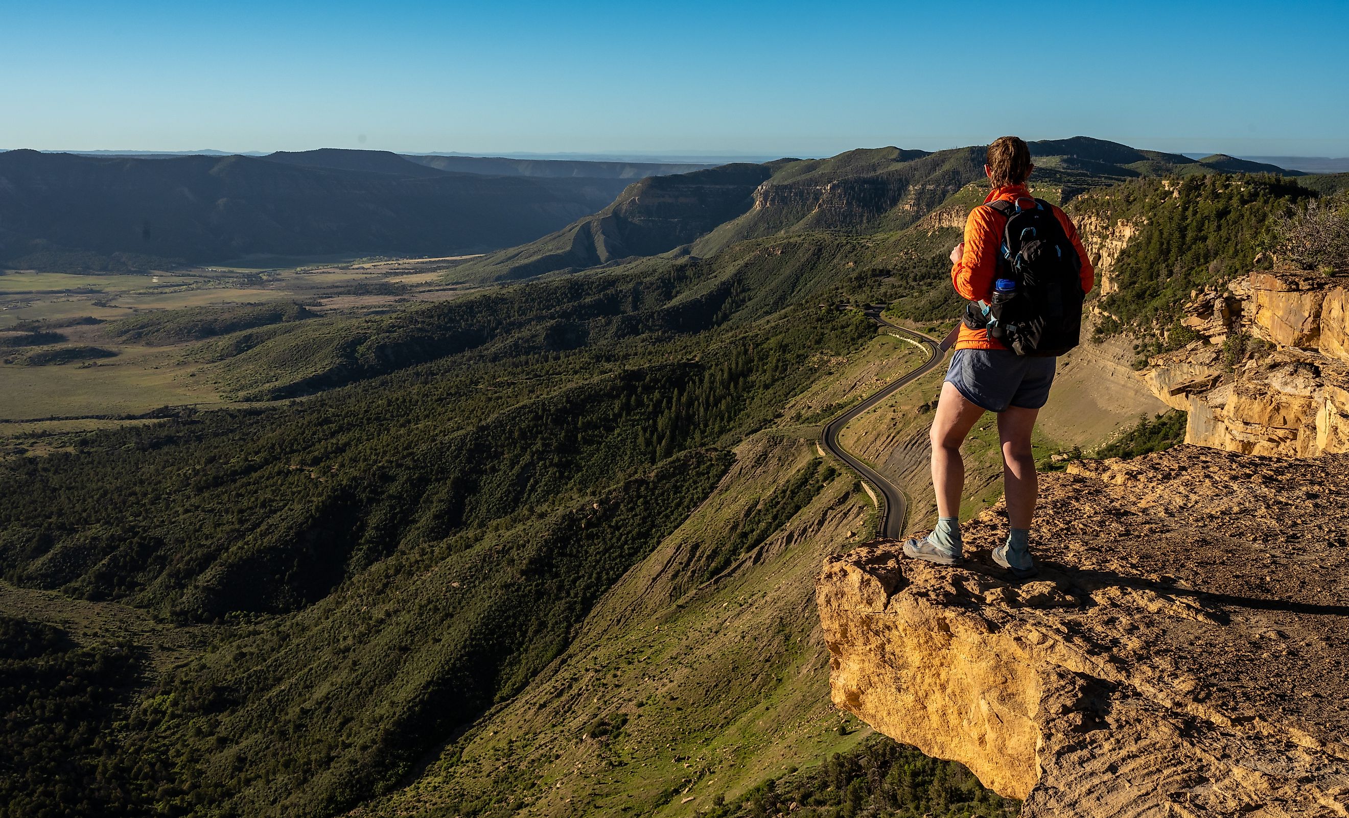 HIker Stands On Rock Shelf Looking Over Mesa Verde National Park