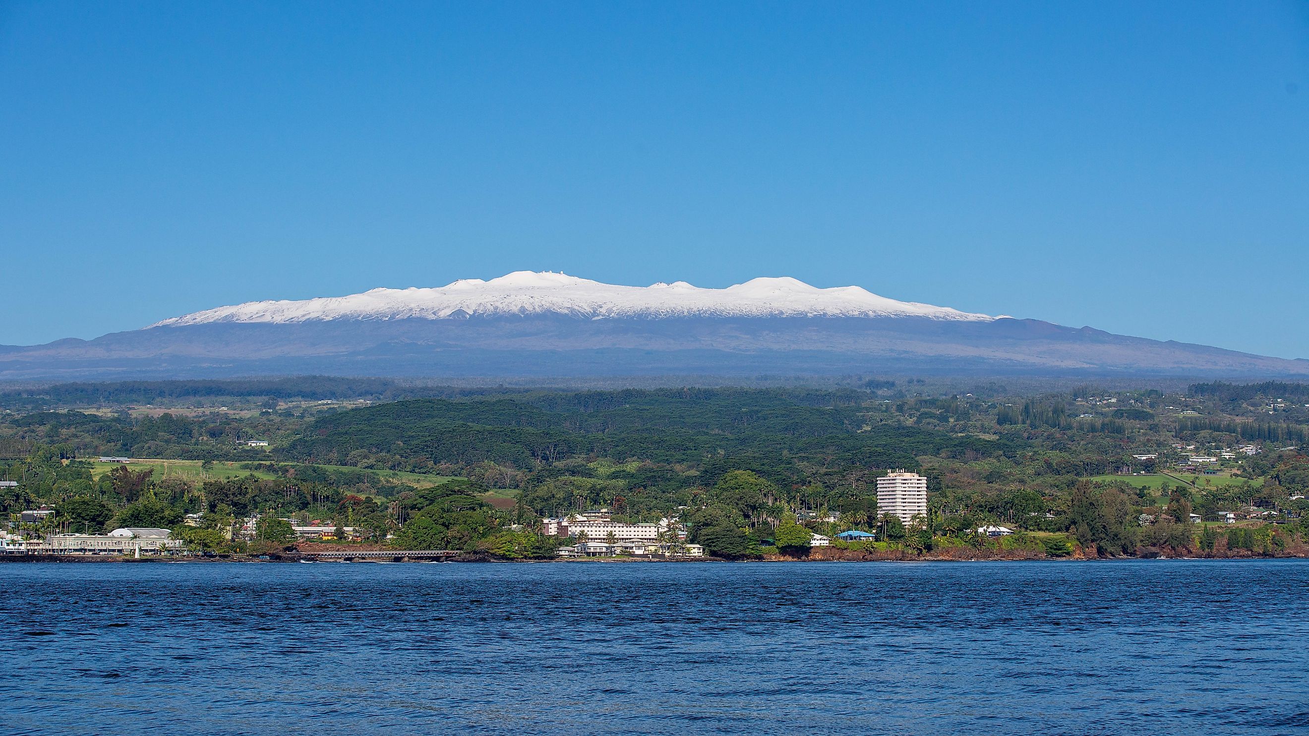 Picture of Hilo, Hawaii on a sunny day with snow-capped Mauna Kea in the background