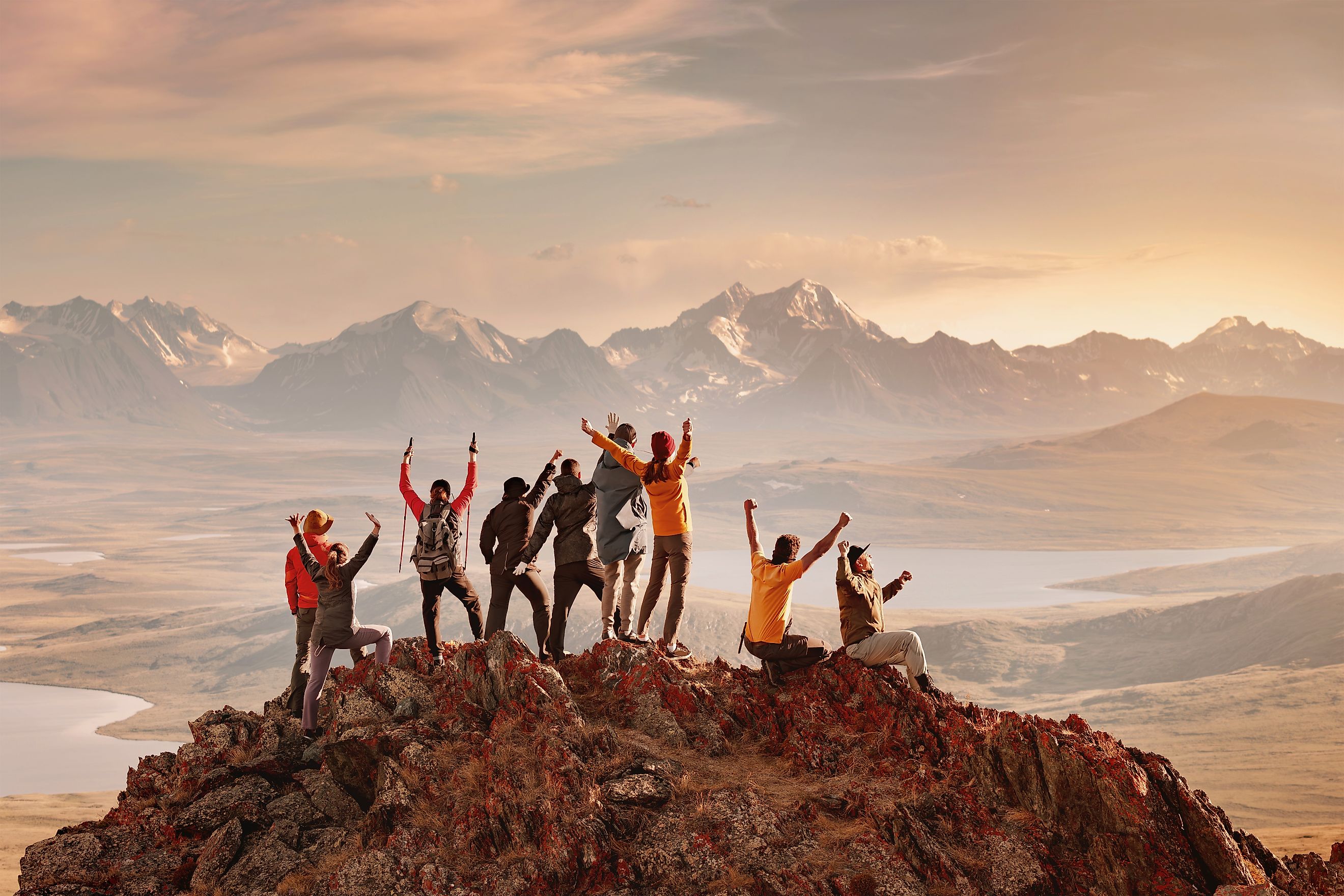 Big group of happy tourists are having fun and greeting sunset at mountain top